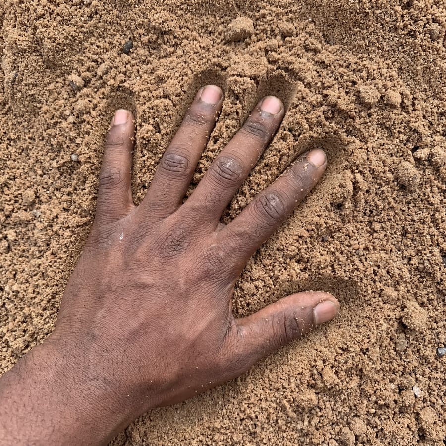 Pit sand texture close-up, hand for scale